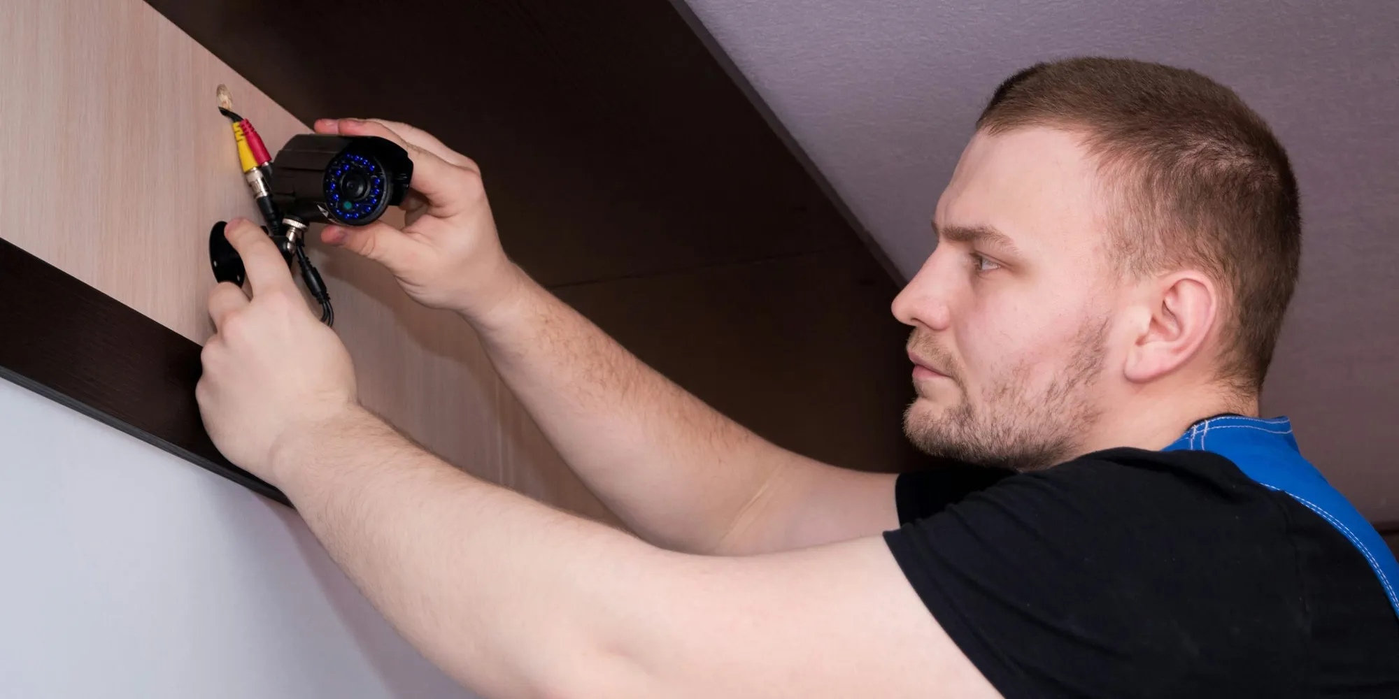 A technician in work clothes fitting a fixture to a wall