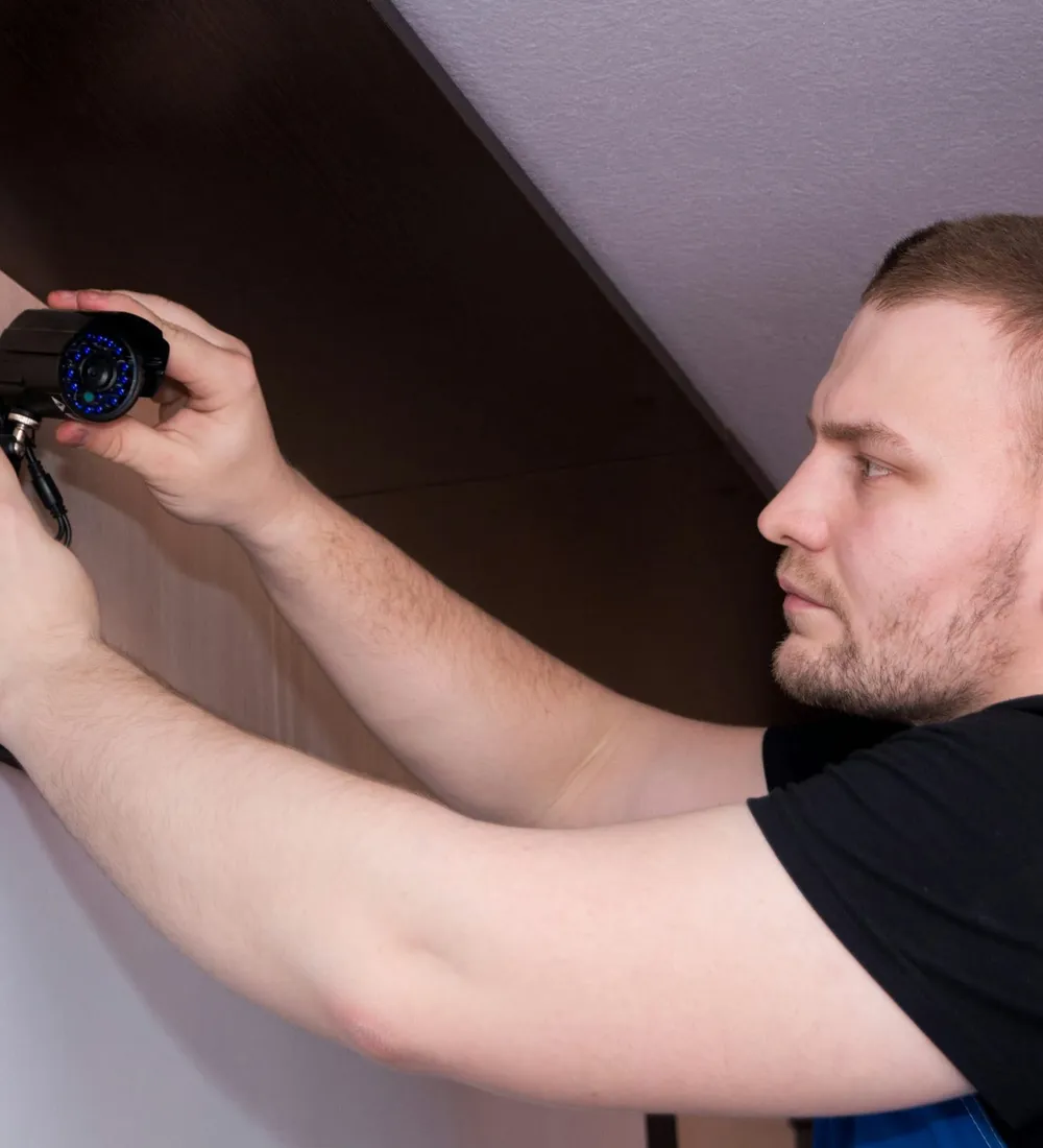 A technician in work clothes fitting a fixture to a wall