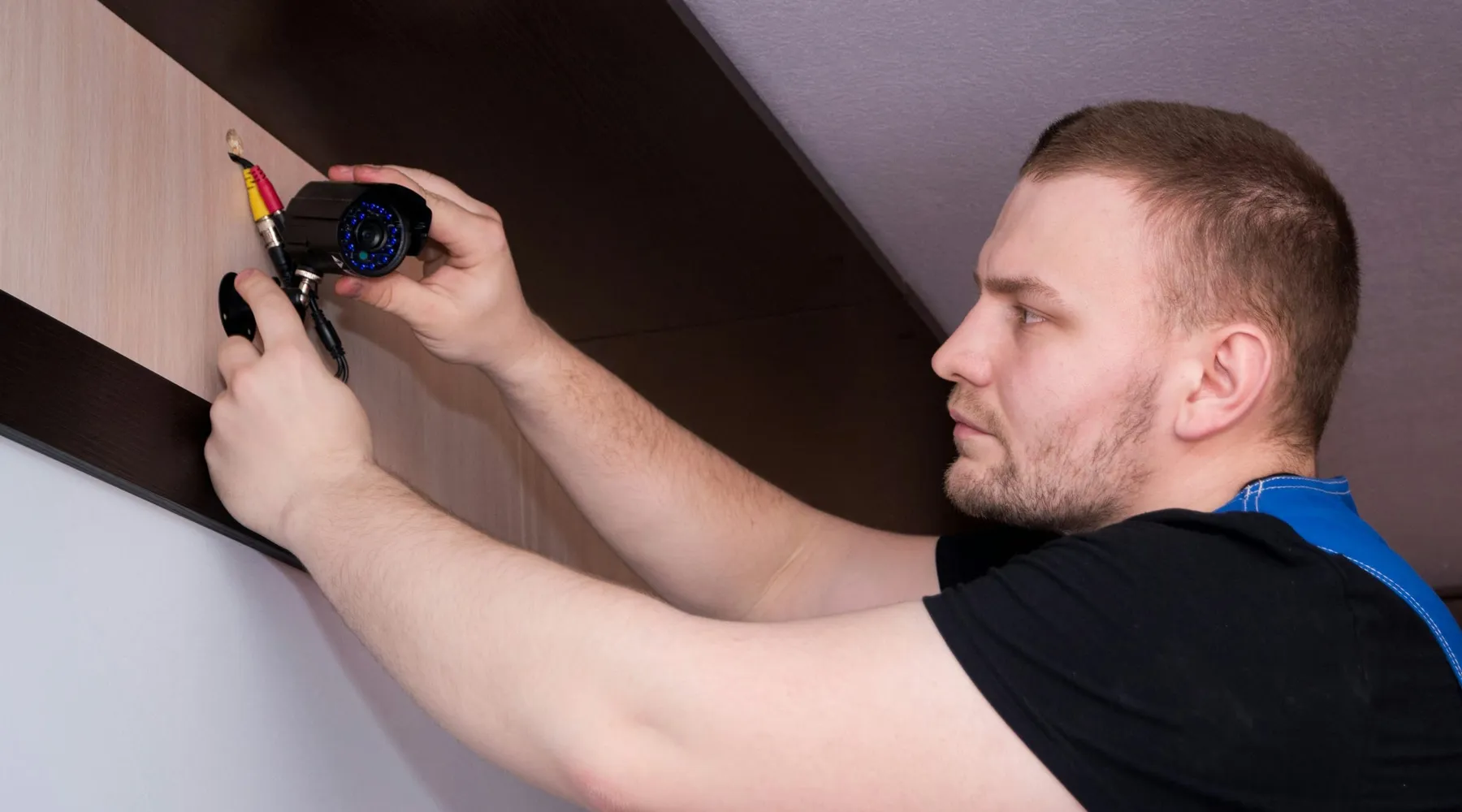 A technician in work clothes fitting a fixture to a wall