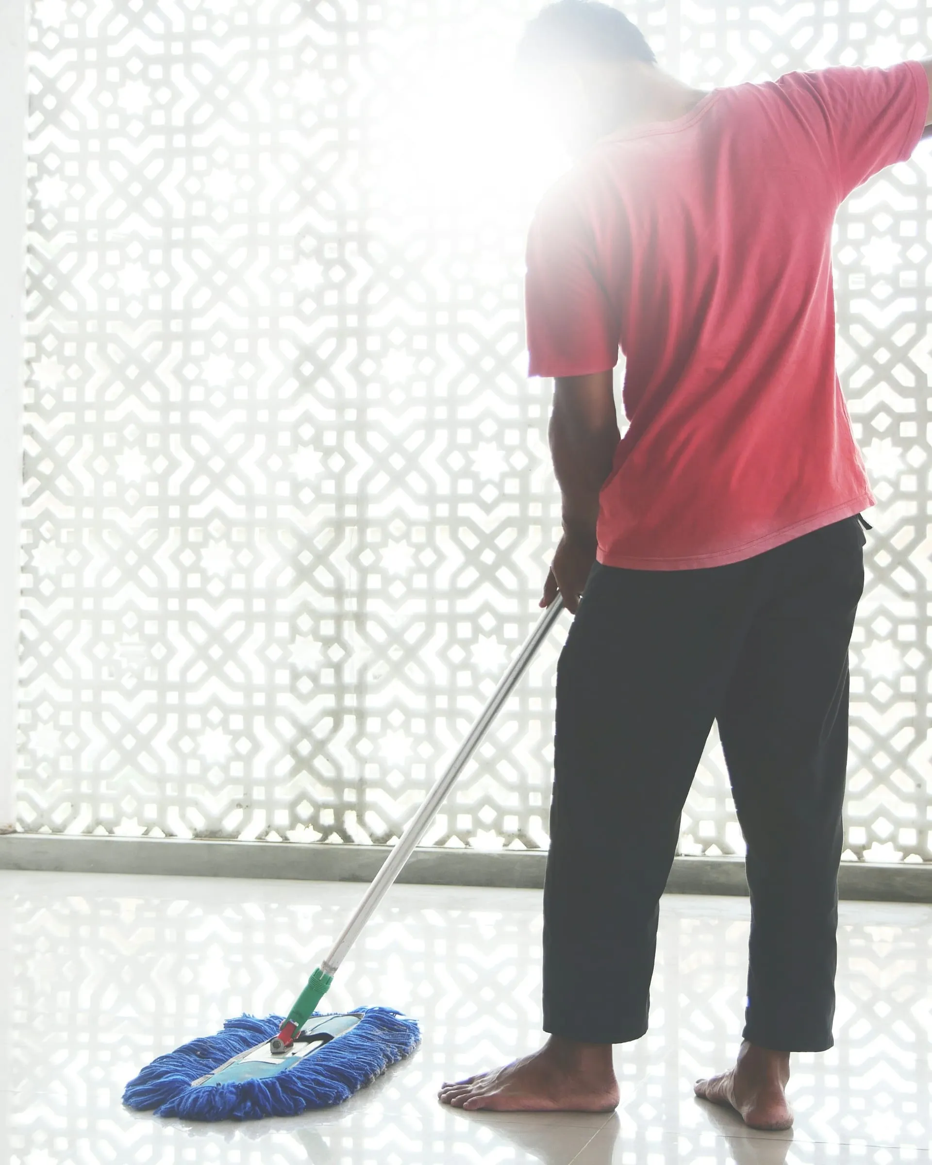 A cleaner mopping a bright office floor