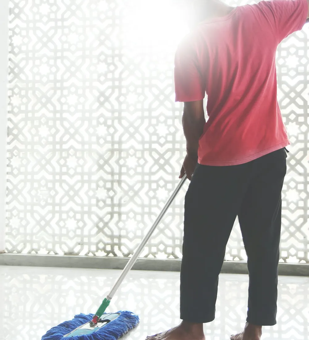 A cleaner mopping a bright office floor