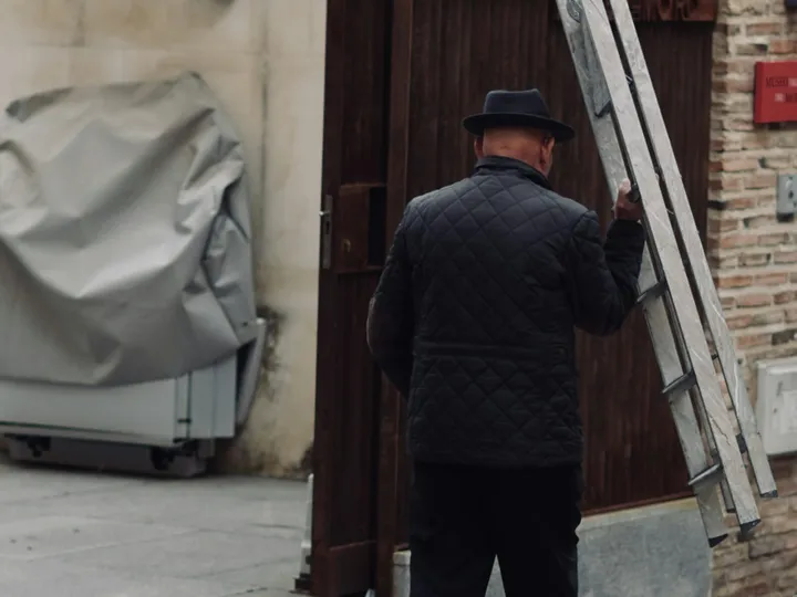 A pro carrying a ladder into a courtyard