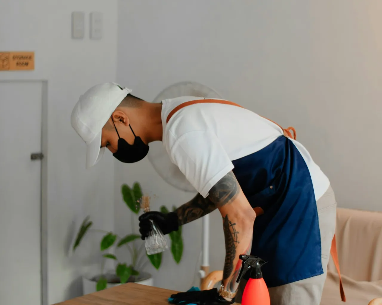 A cleaner wiping down a wooden dining table