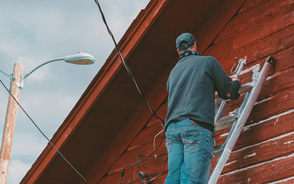 A crew member on a ladder at the gutter line