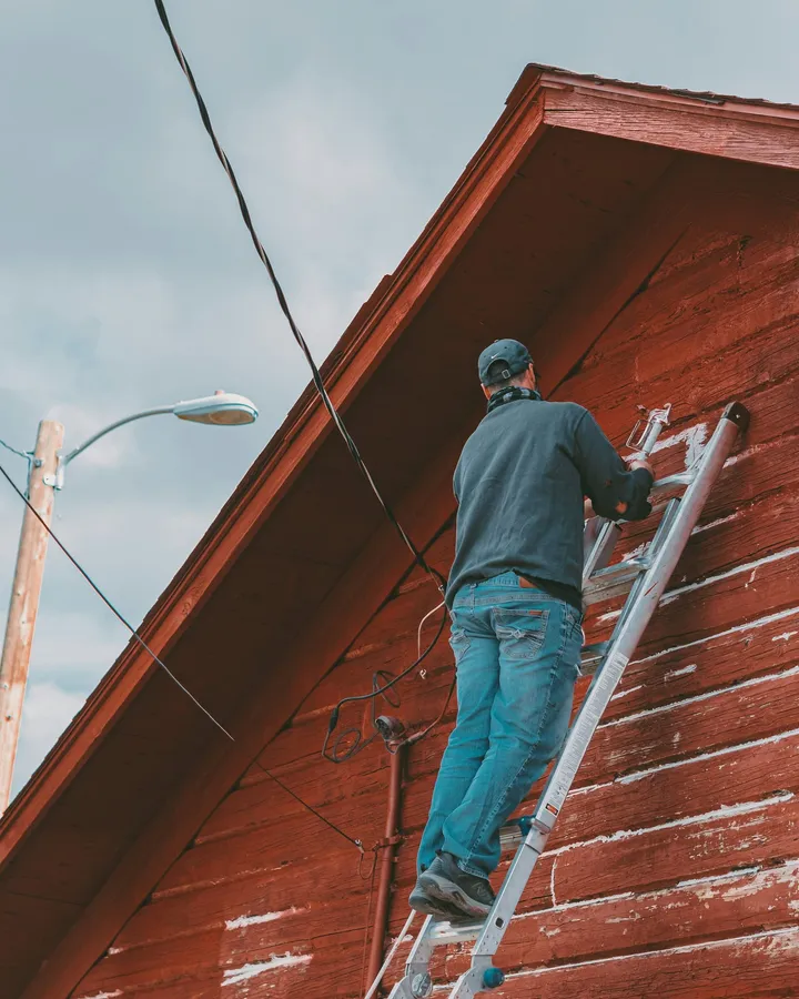 A pro on a ladder at a red gutter