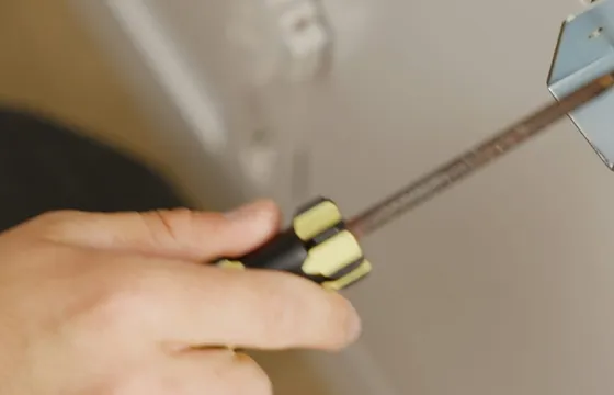 A hand driving a screw with a screwdriver