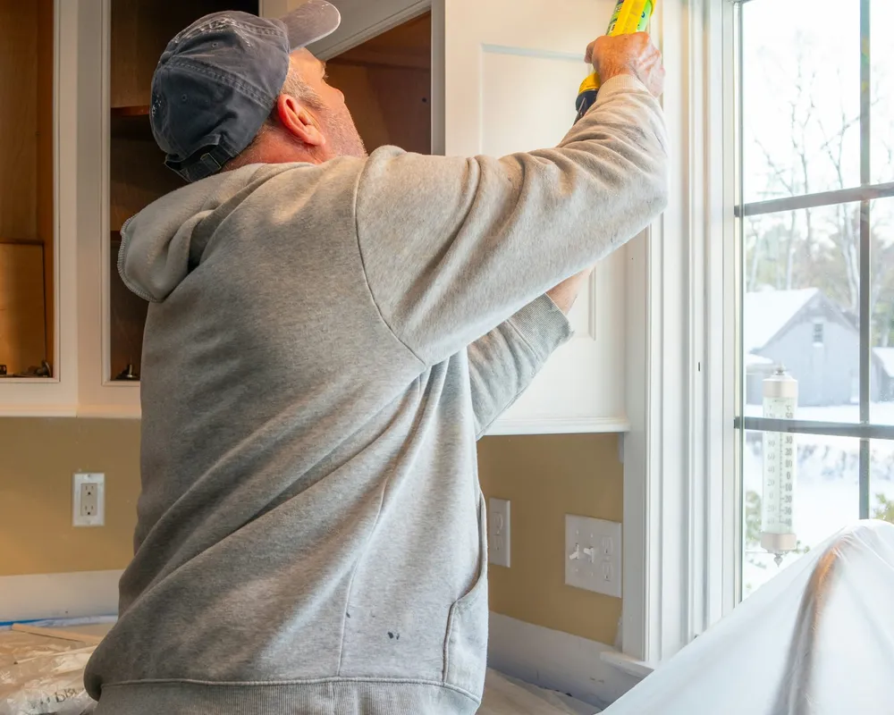 A handyman fitting a kitchen cabinet door