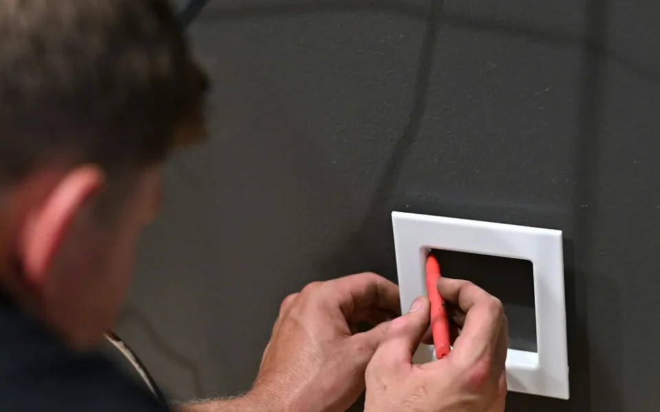 A handyman fitting a switch plate
