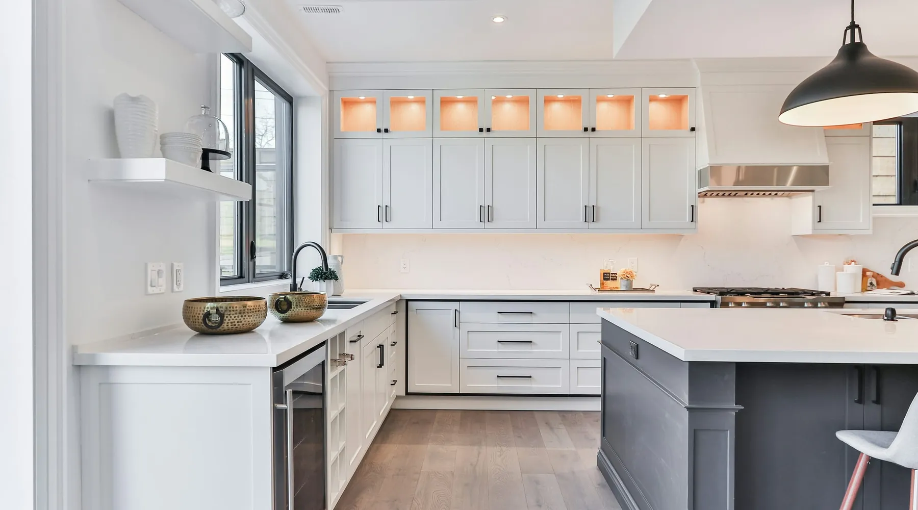 A bright white kitchen with an island and pendant lights