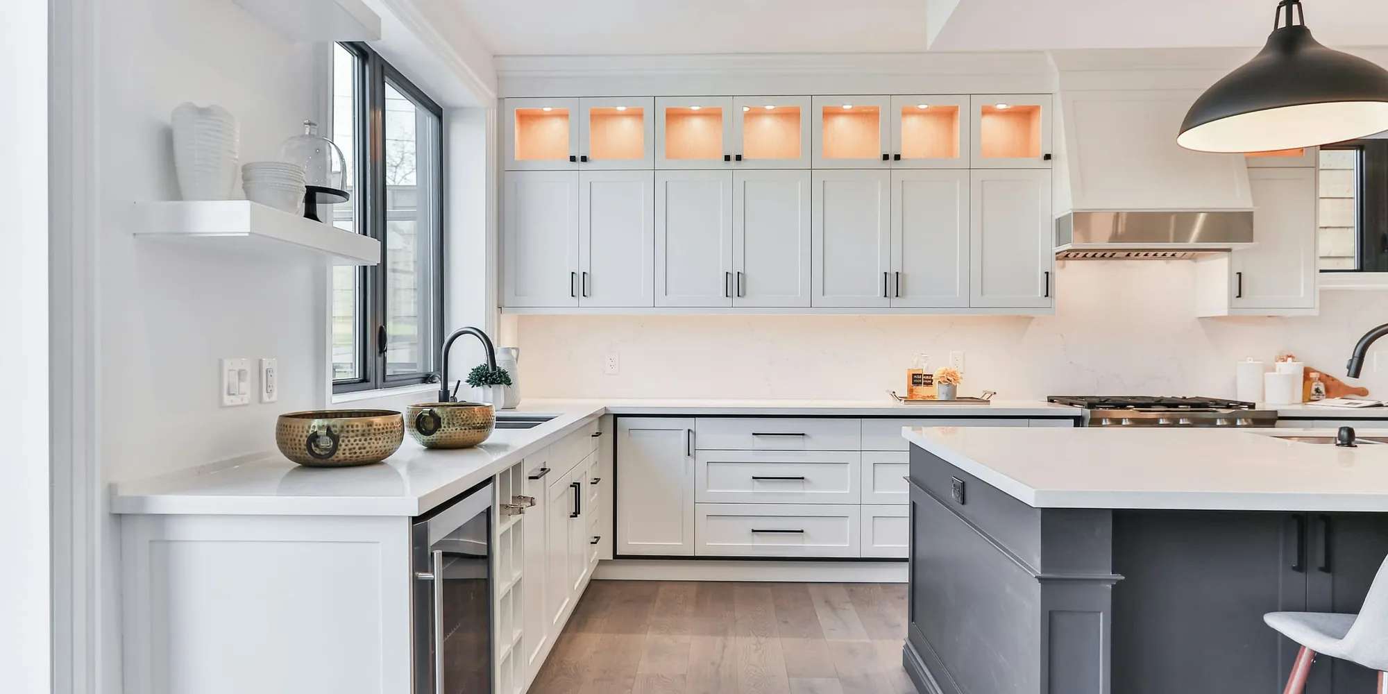 A bright white kitchen with an island and pendant lights