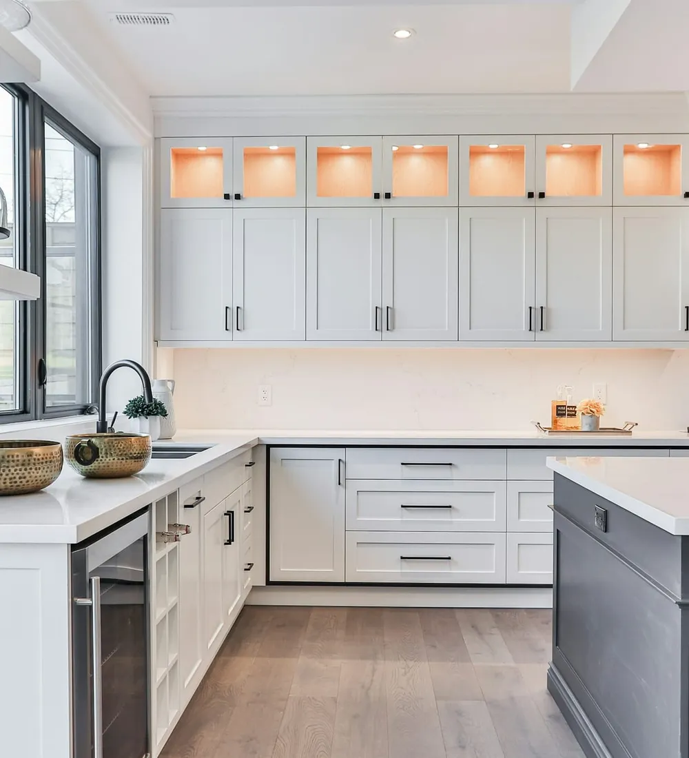 A bright white kitchen with an island and pendant lights