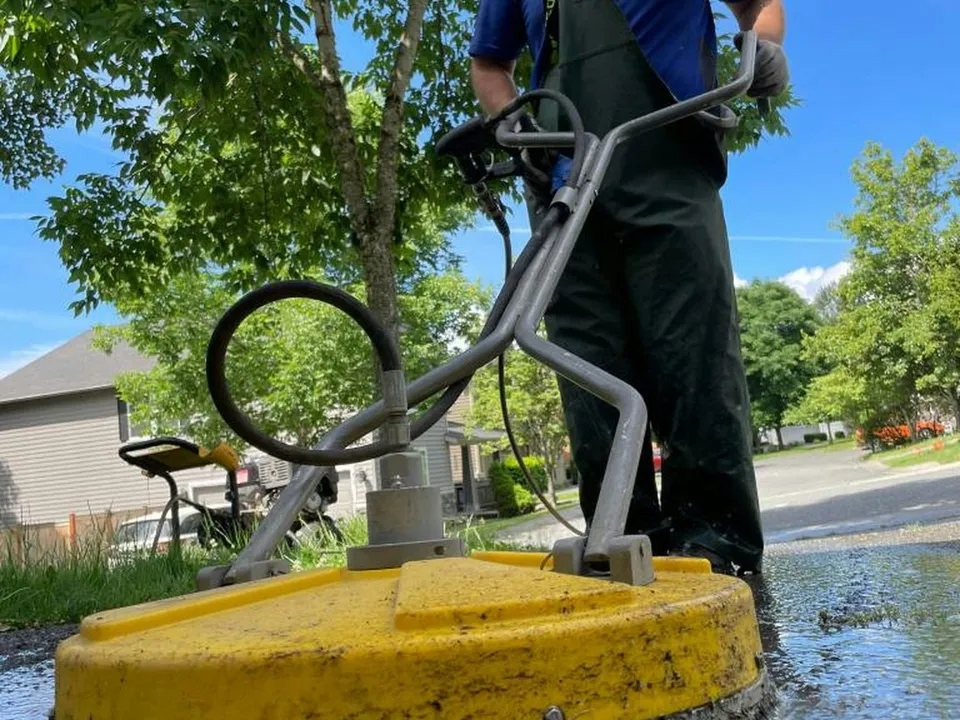 A smiling pro cleaning a patio with a surface cleaner