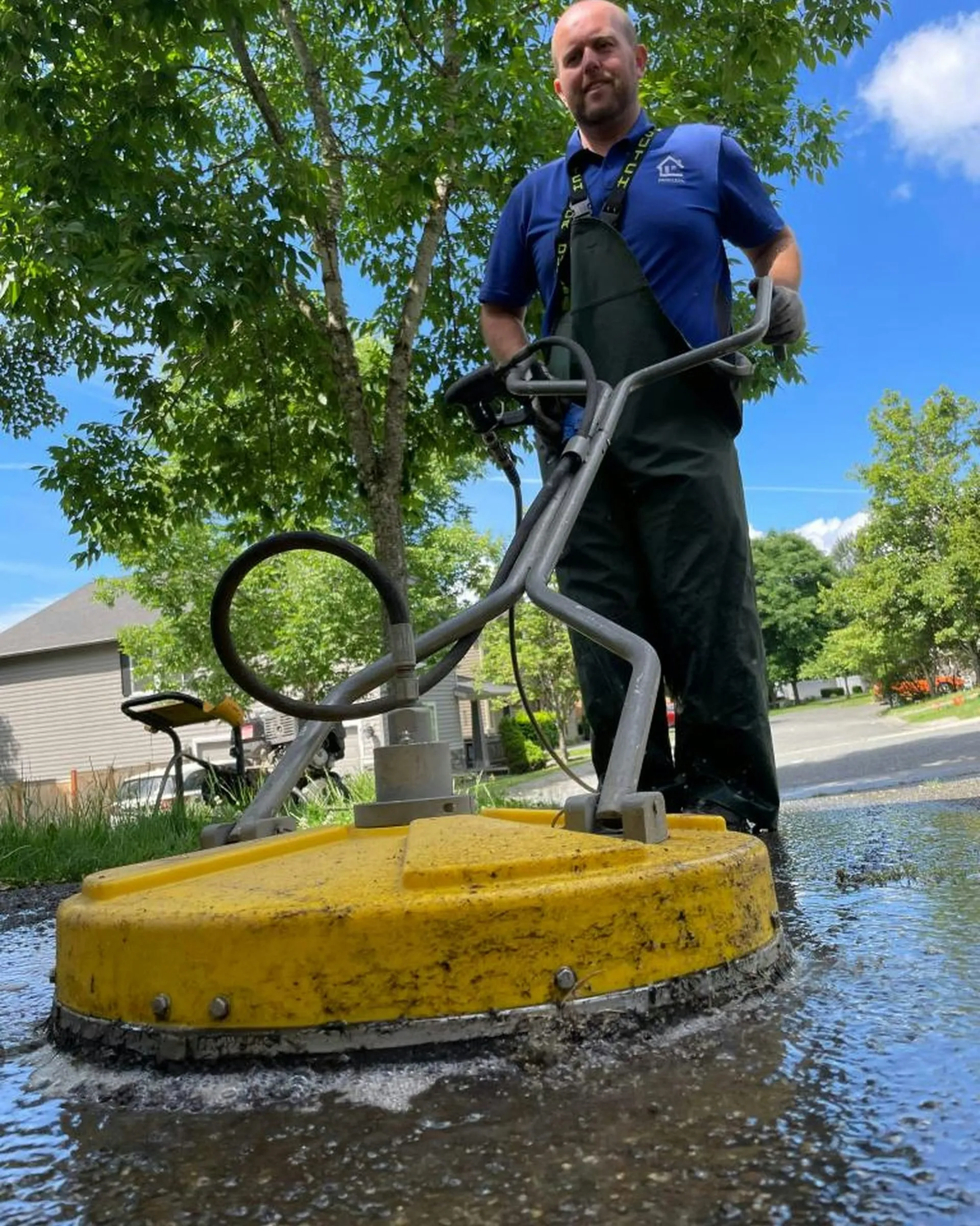 A smiling pro cleaning a patio with a surface cleaner