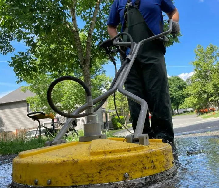 A crew member cleaning a forecourt with a surface cleaner