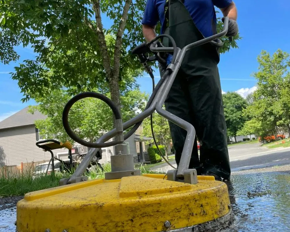 A smiling pro cleaning a patio with a surface cleaner