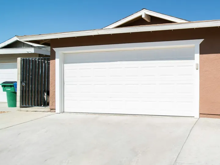 A clean driveway in front of a white garage door