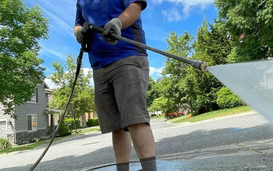 A crew member pressure-washing a driveway