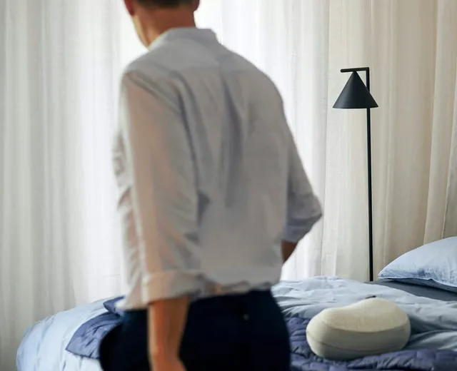 A crew member making a bed in a bright bedroom