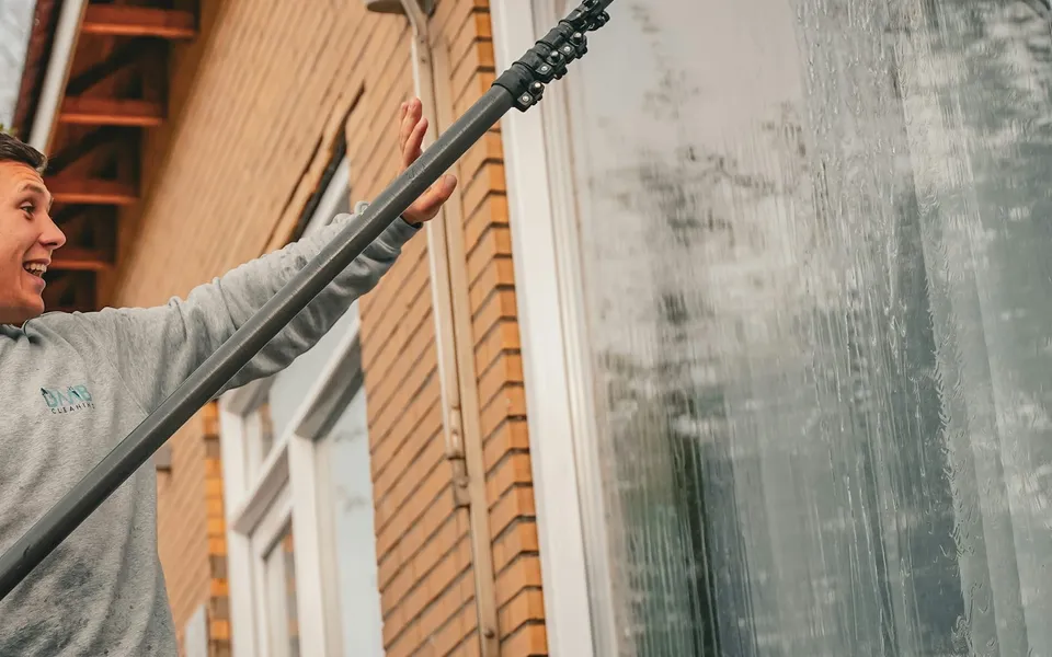 A window cleaner working with a water-fed pole